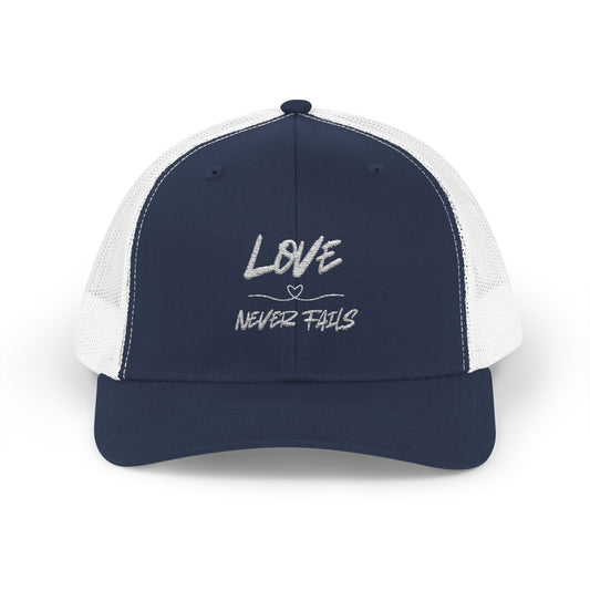LOVE NEVER FAILS TRUCKER HAT